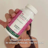 Close-up of a hand holding the Vitamin B12 dietary supplement bottle, opening the lid, and pouring out smooth, white capsules—showcasing the product for daily use to support energy, immune system, nervous system, and reduce tiredness.